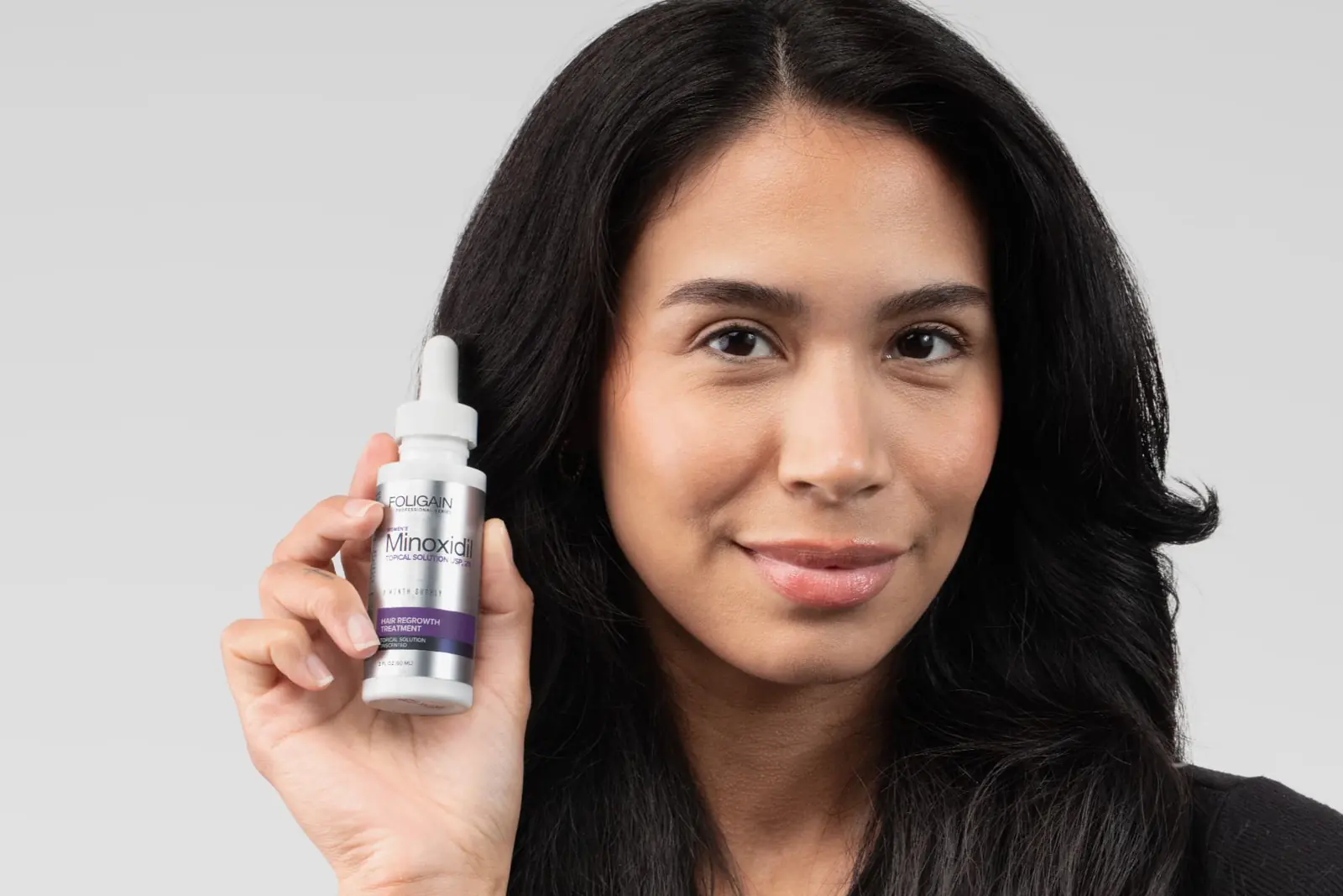 Woman holding a Minoxidil 2% bottle