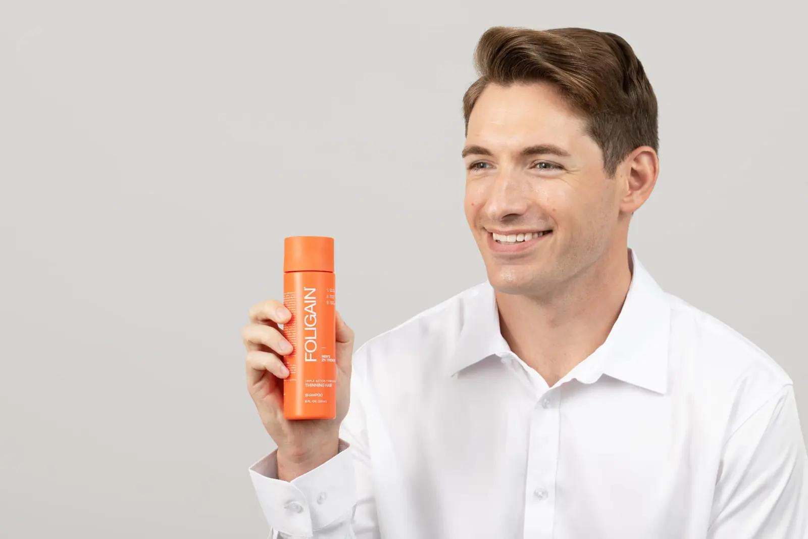 Man holding orange FOLIGAIN® shampoo