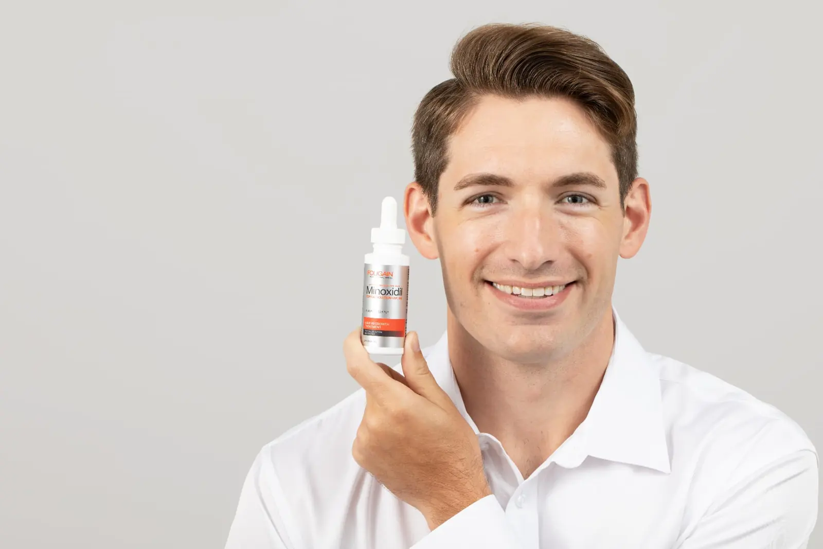 Man holding a FOLIGAIN® Minoxidil 5% bottle