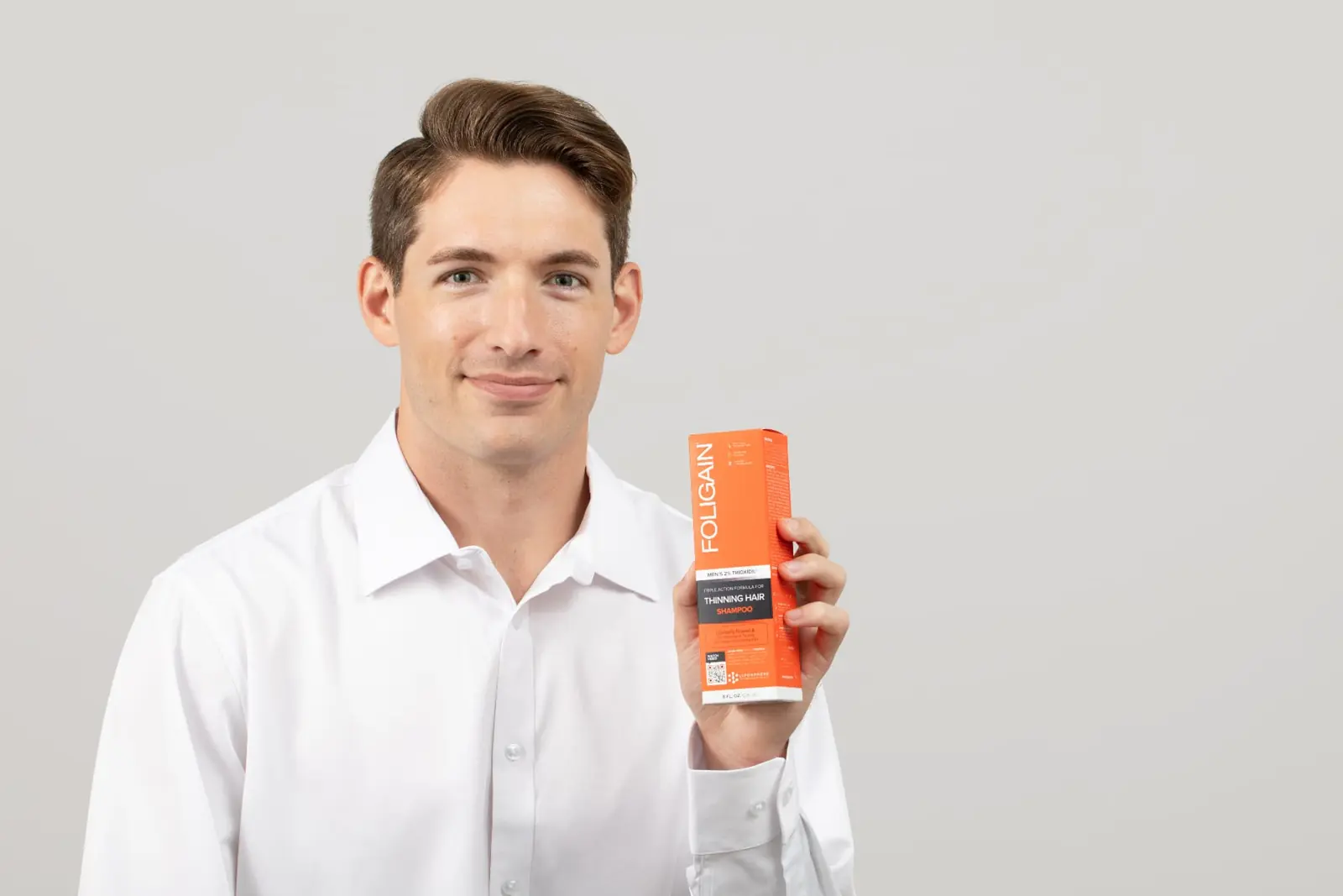 Man holding a thinning hair shampoo box