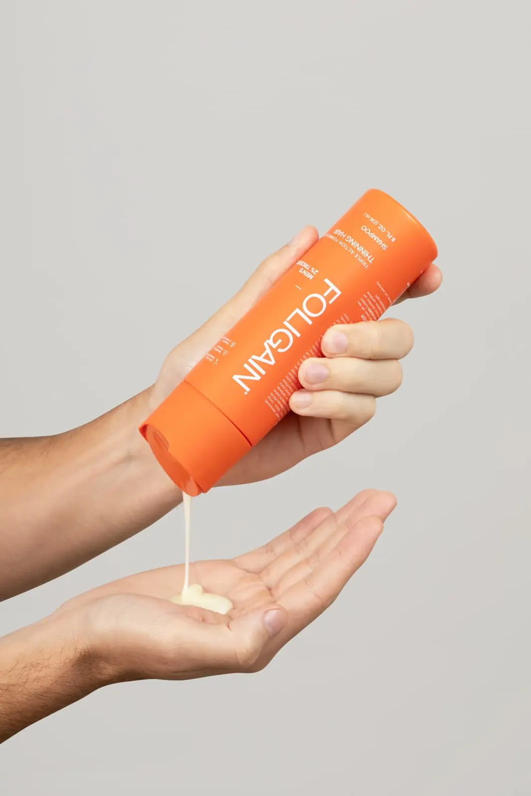 Pouring FOLIGAIN® shampoo into a hand