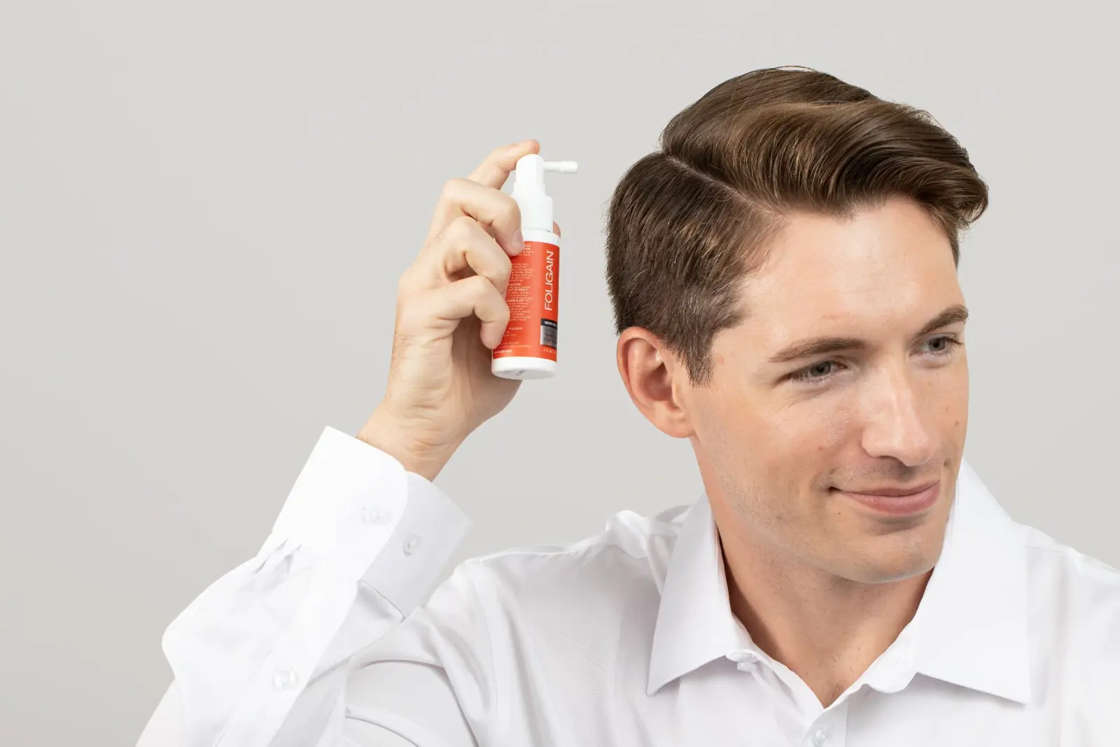 Man applying FOLIGAIN® TRIOXIDIL® spray