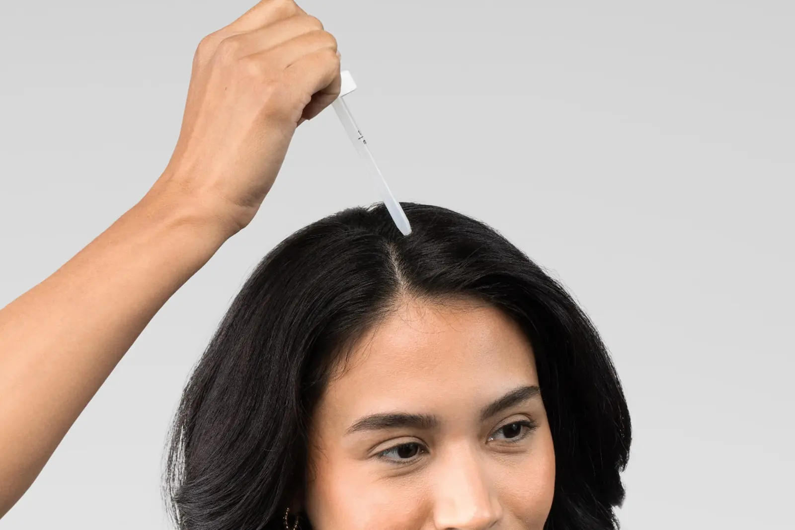 Woman applying Minoxidil with a dropper